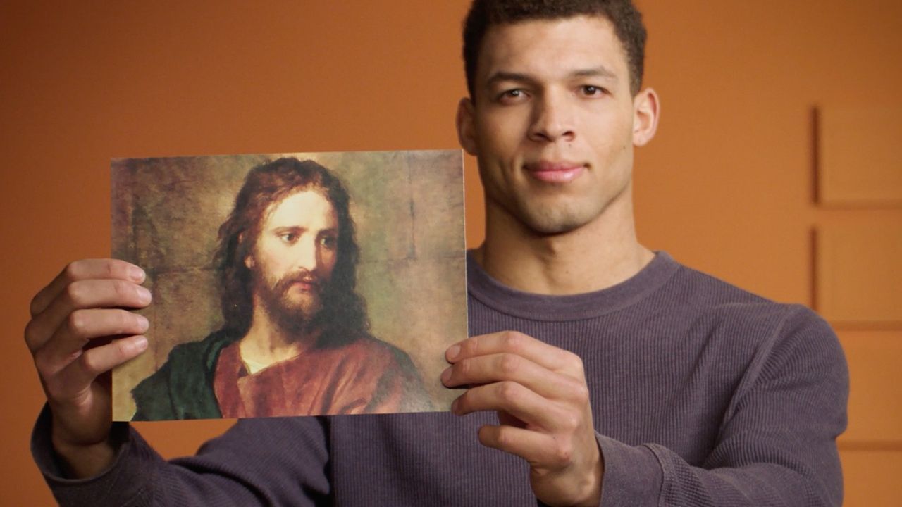 A man holding up a picture of Jesus Christ