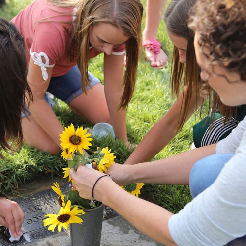 girls placing sunflowers at grave