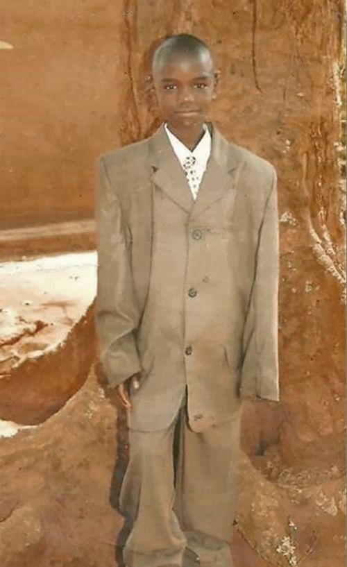 Joseph Ssengooba as a boy wearing an over sized suit.