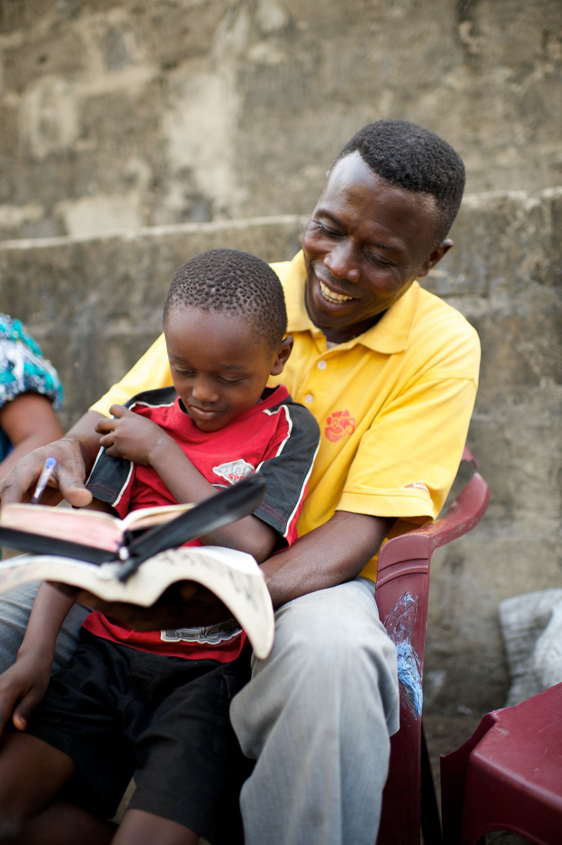 A father and his son sit outside together and read from the scriptures.