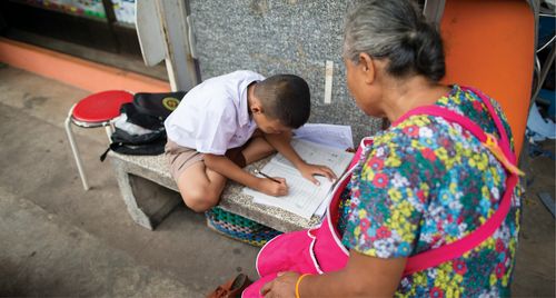 Una abuela ayuda a un niño a estudiar.