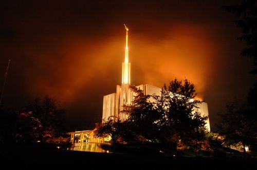 The Seattle Washington Temple during a storm, with the temple lit up at night.