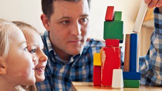 father and children playing with blocks