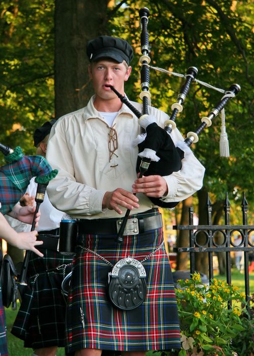 A young man in a kilt playing a bagpipe.