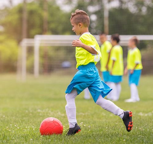 boy with blue shorts and yellow shirt playing football (soccer)