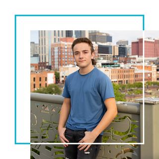 A young man in Tennessee stands outside and smiles to the camera.