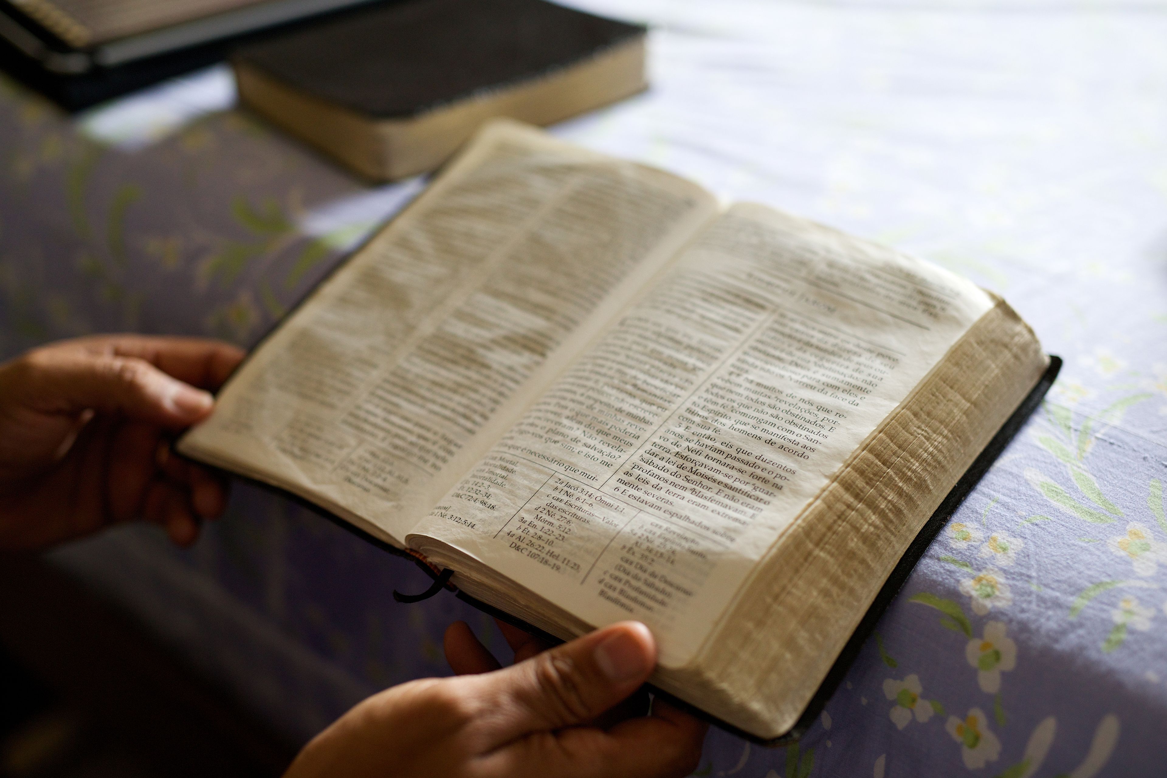 A well-used hardbound set of Portuguese scriptures being held open on a table.