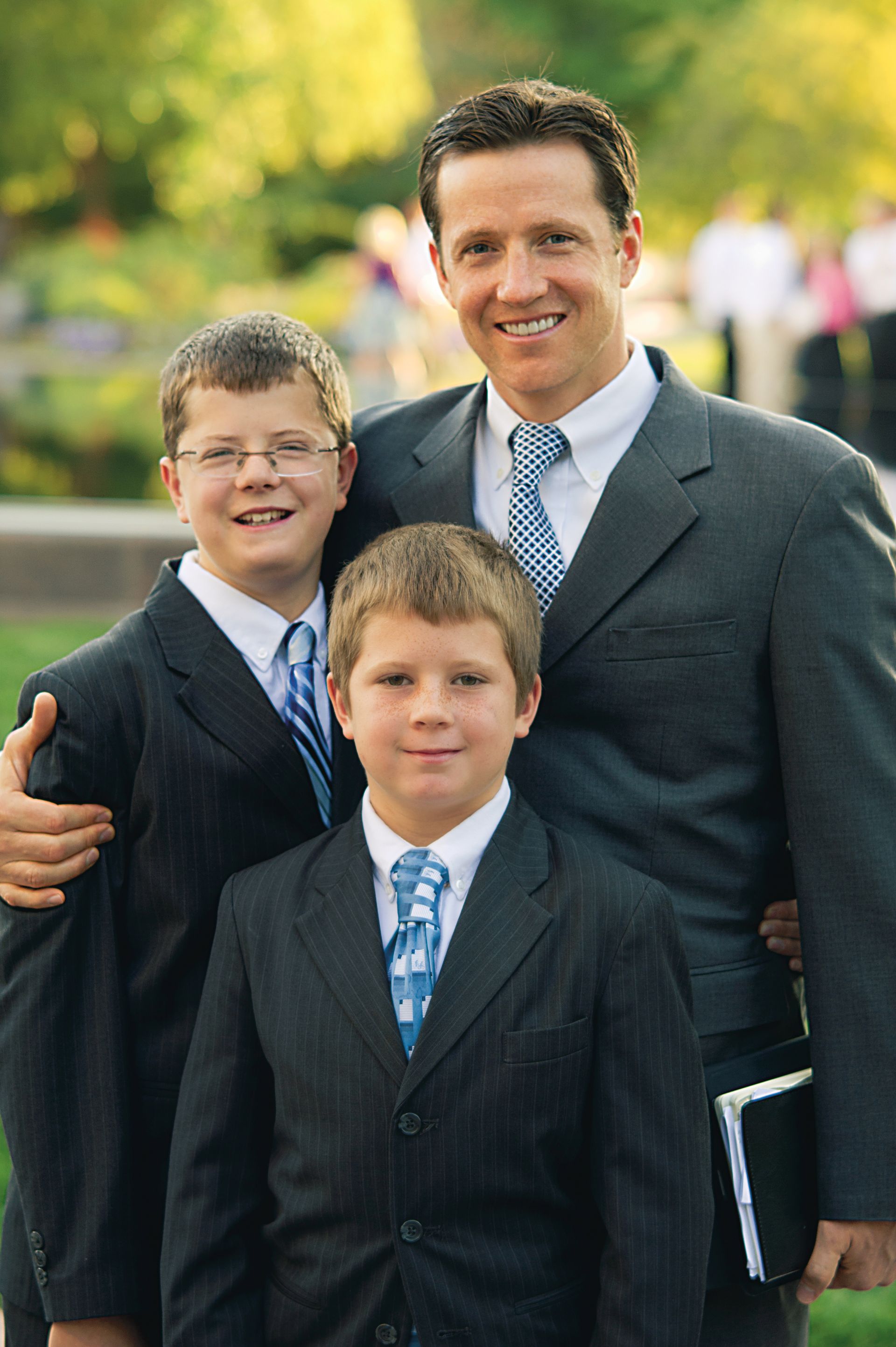 A father and his two sons standing outside before a session of general conference.