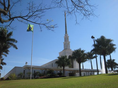 The entire São Paulo Brazil Temple, including a view of the grounds, with palm trees and a partial view of the fountain in front of the temple.