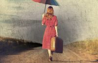 woman walking with umbrella and suitcase