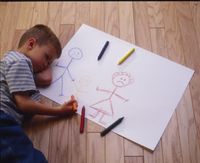 A child lying on a wooden floor as he colors a picture. The picture depicts three stick figures one in each primary color. All have frowns. Mother is separated from the child and father. The father holds the hand of the child, and the child is between the parents. The image is designed to illustrate a child's feelings about the divorce of his parents.