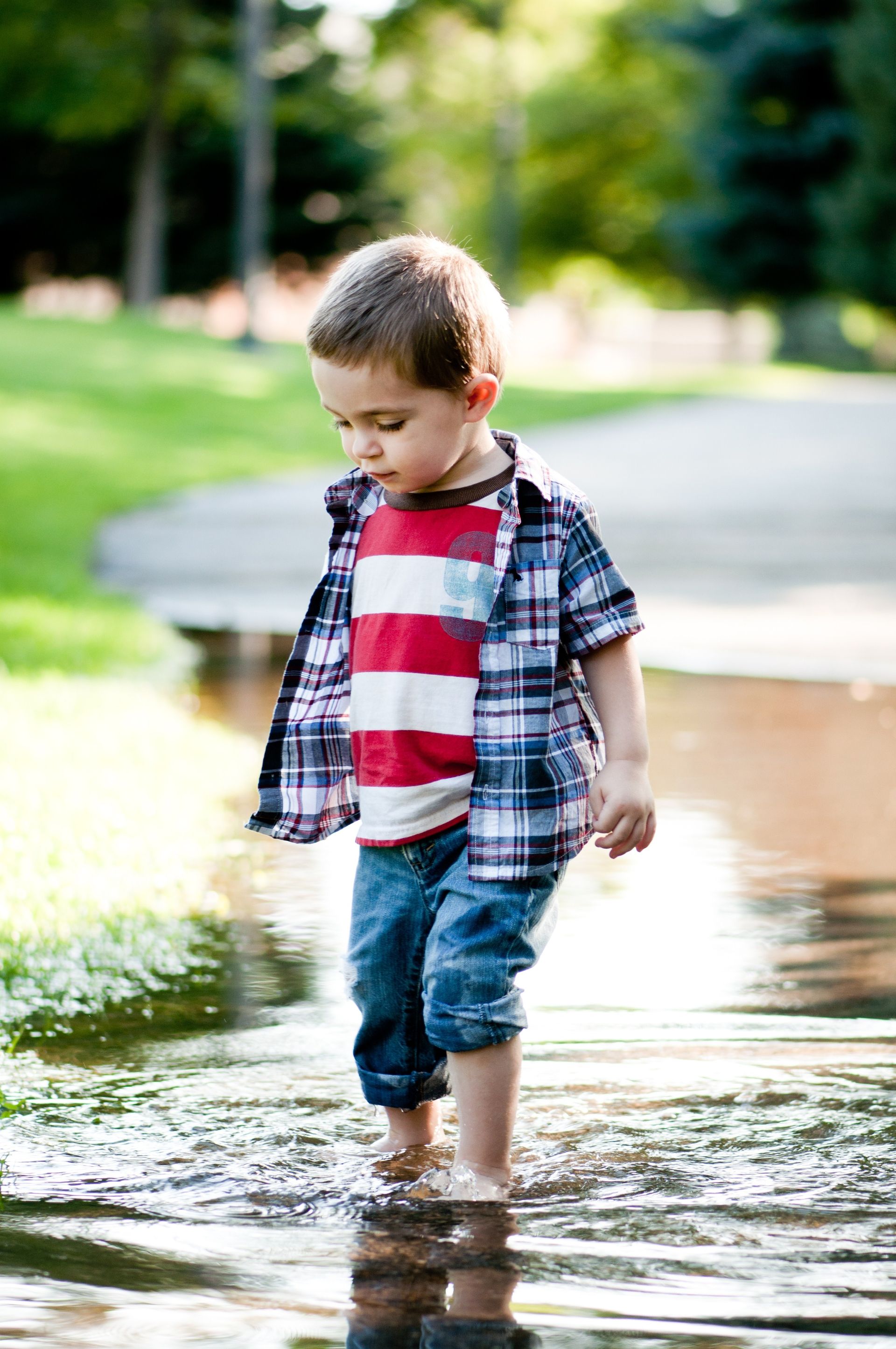 A toddler boy walking in water.