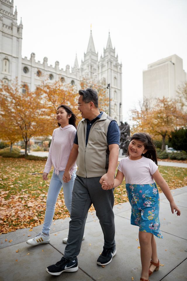 A family is together. They are walking around Temple Square talkig and laughing. You can see the Salt Lake Temple behind them.