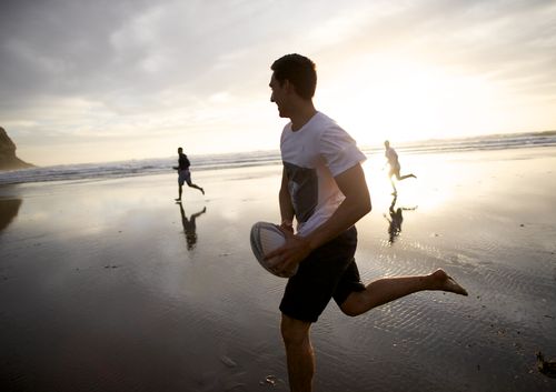 mænd spiller rugby på stranden