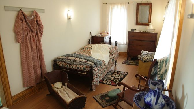 Bedroom setting with cradle, bed, rocking chair, and other furnishings.