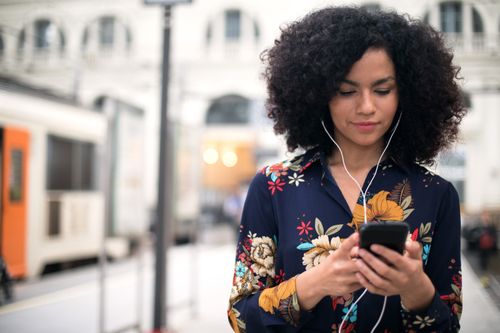 young woman looking at phone near train