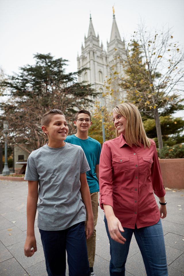 A family is together. They are walking around Temple Square talkig and laughing. You can see the Salt Lake Temple behind them.