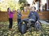 Man in wheelchair with children playing in leaves