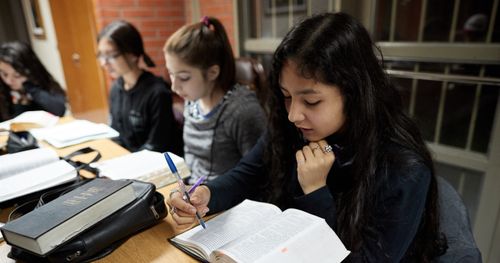 Young men and young women attend an early morning seminary class in Argentina.