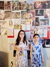 Carmen and Karys standing in front of wall covered with pictures of Jesus