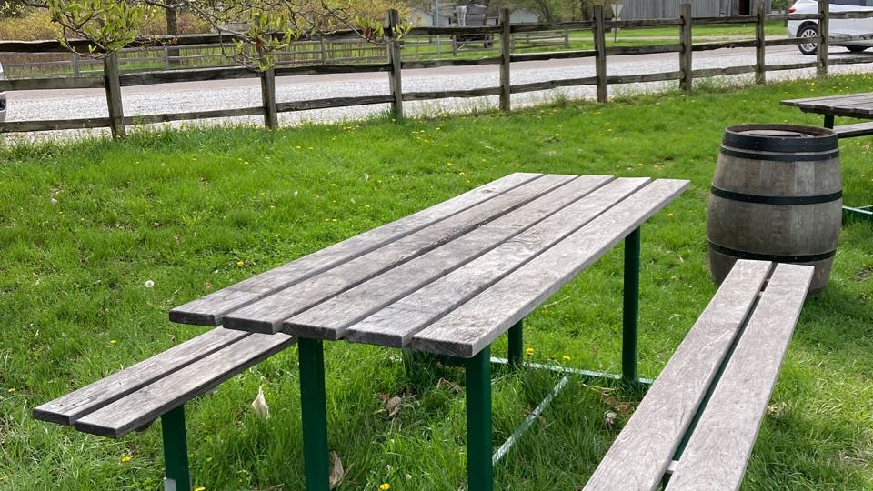 Close up of a picnic table in a grassy area with a wooden fence in the background.