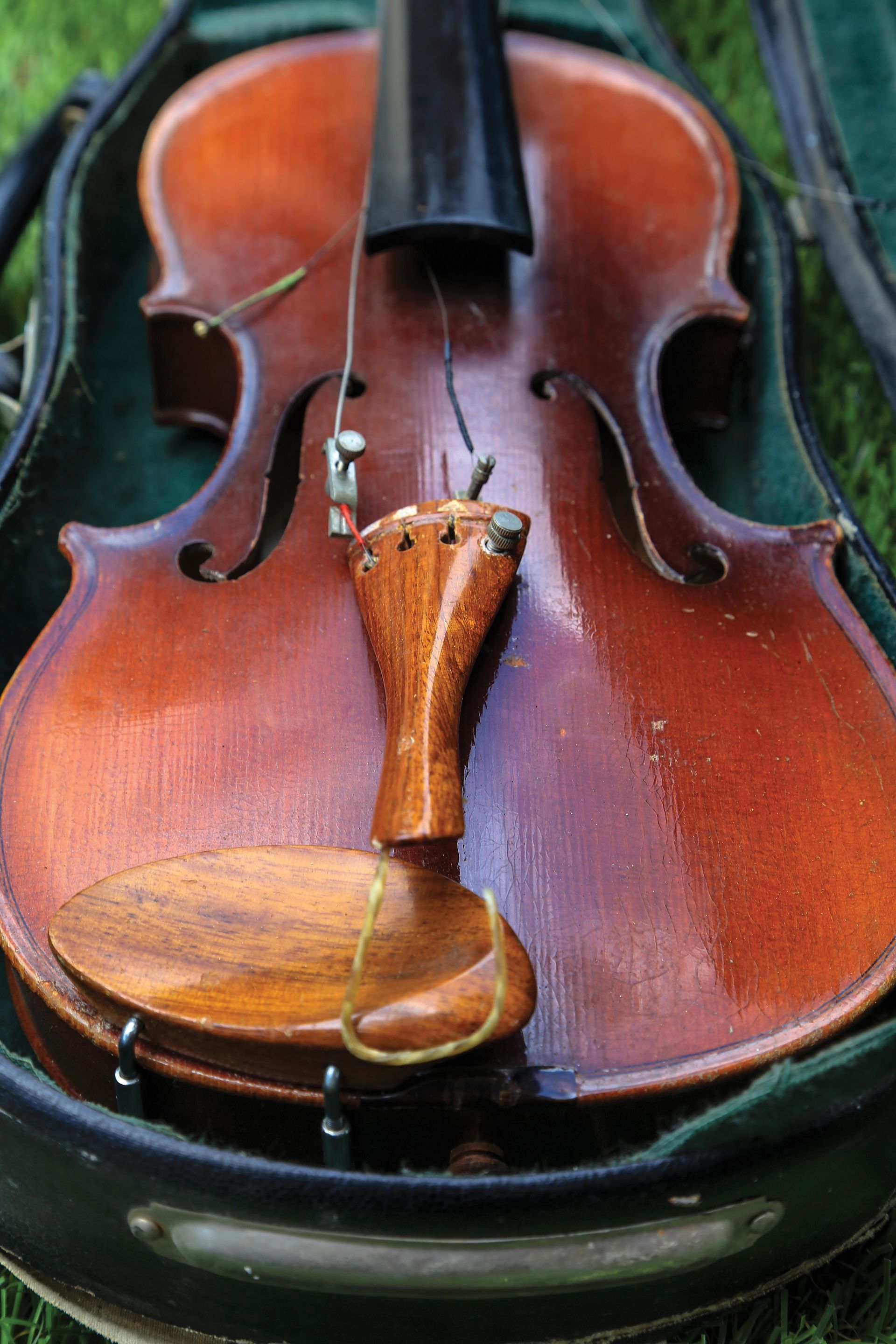 A violin with broken strings lying in a case.