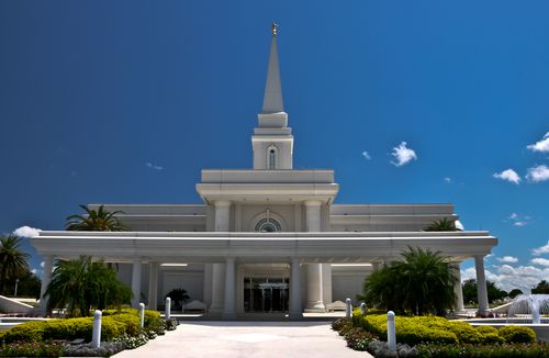 The front and entrance of the Orlando Florida Temple on a sunny day, with a nearly clear, vibrant blue sky overhead.