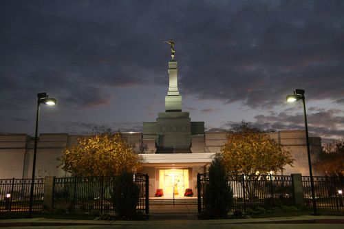 The entrance to the Fresno California Temple in the evening, with the lights illuminating the temple against the dark gray sky.