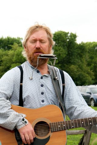 A performer plays his guitar and harmonica and sings at the Nauvoo Pageant.