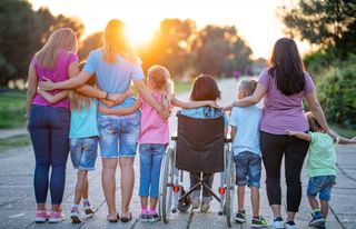 Rear view group of people supporting young women on a wheelchair