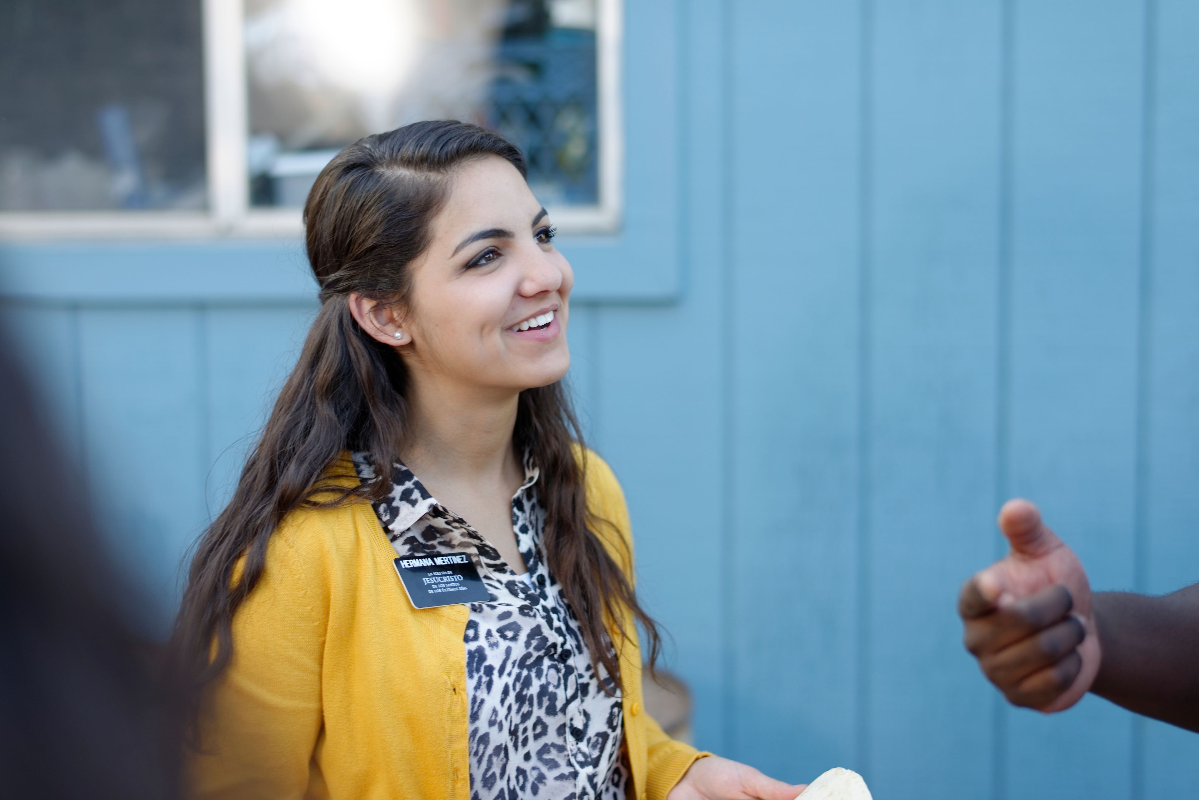 A sister missionary smiling as a person talks to her.