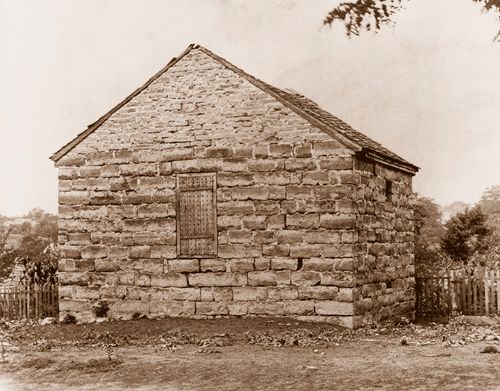 Black and white photo of a small, crude brick building