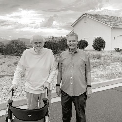 twee mannen op straat, één houdt zich vast aan een looprek