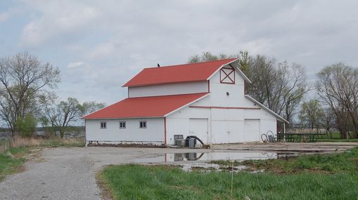 Large white barn with a red roof.