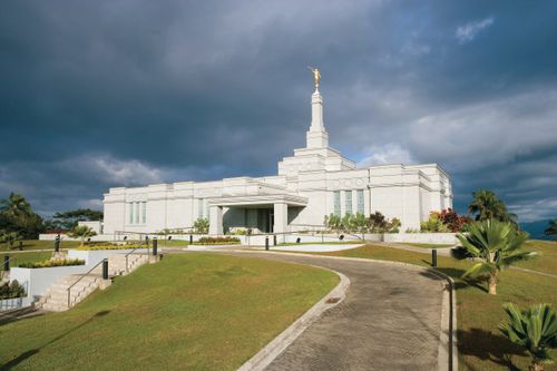 The entire Suva Fiji Temple, with stairs leading up to the entrance, a partial view of the grounds, and a path that goes through the grounds.