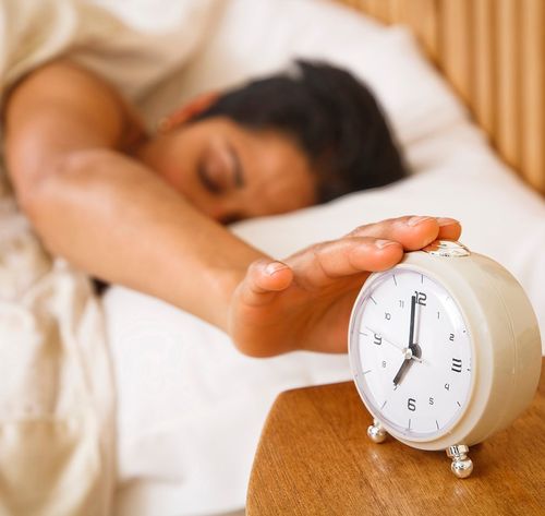 woman snoozing alarm clock