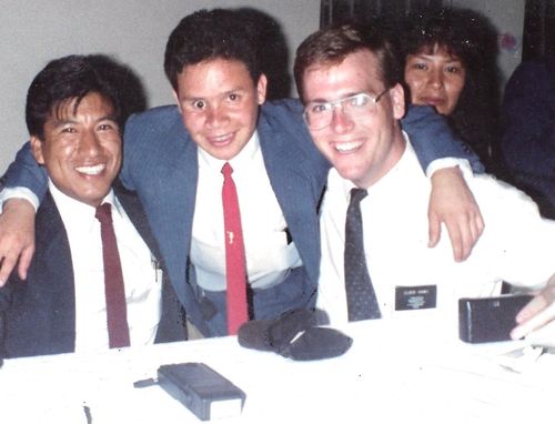 Manuel Navarro smiles at the camera with his arms around two other missionaries.