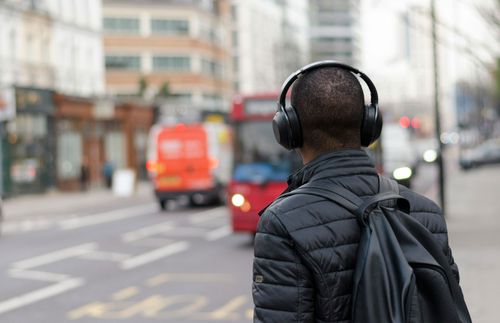 a man with headphones waiting for a bus