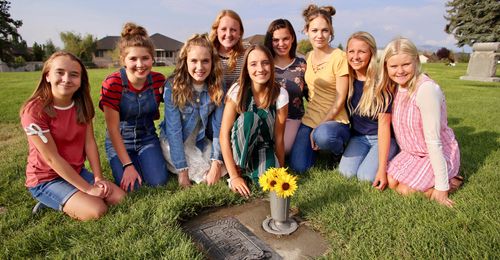 girls at grave with sunflowers