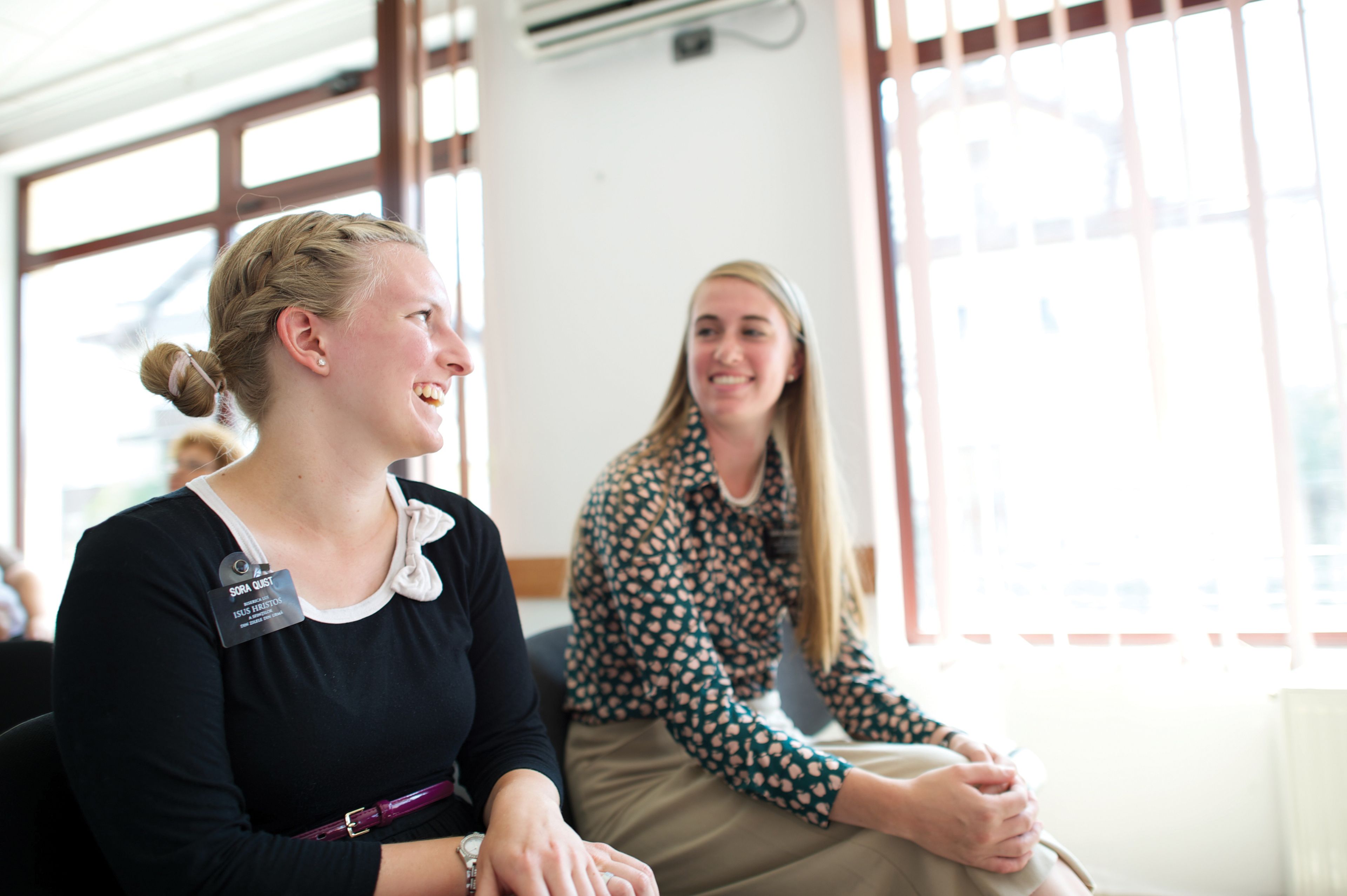 Sister missionaries look at each other and laugh.