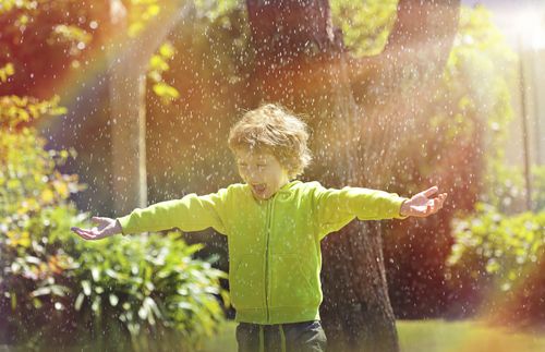 boy playing in garden under the rain