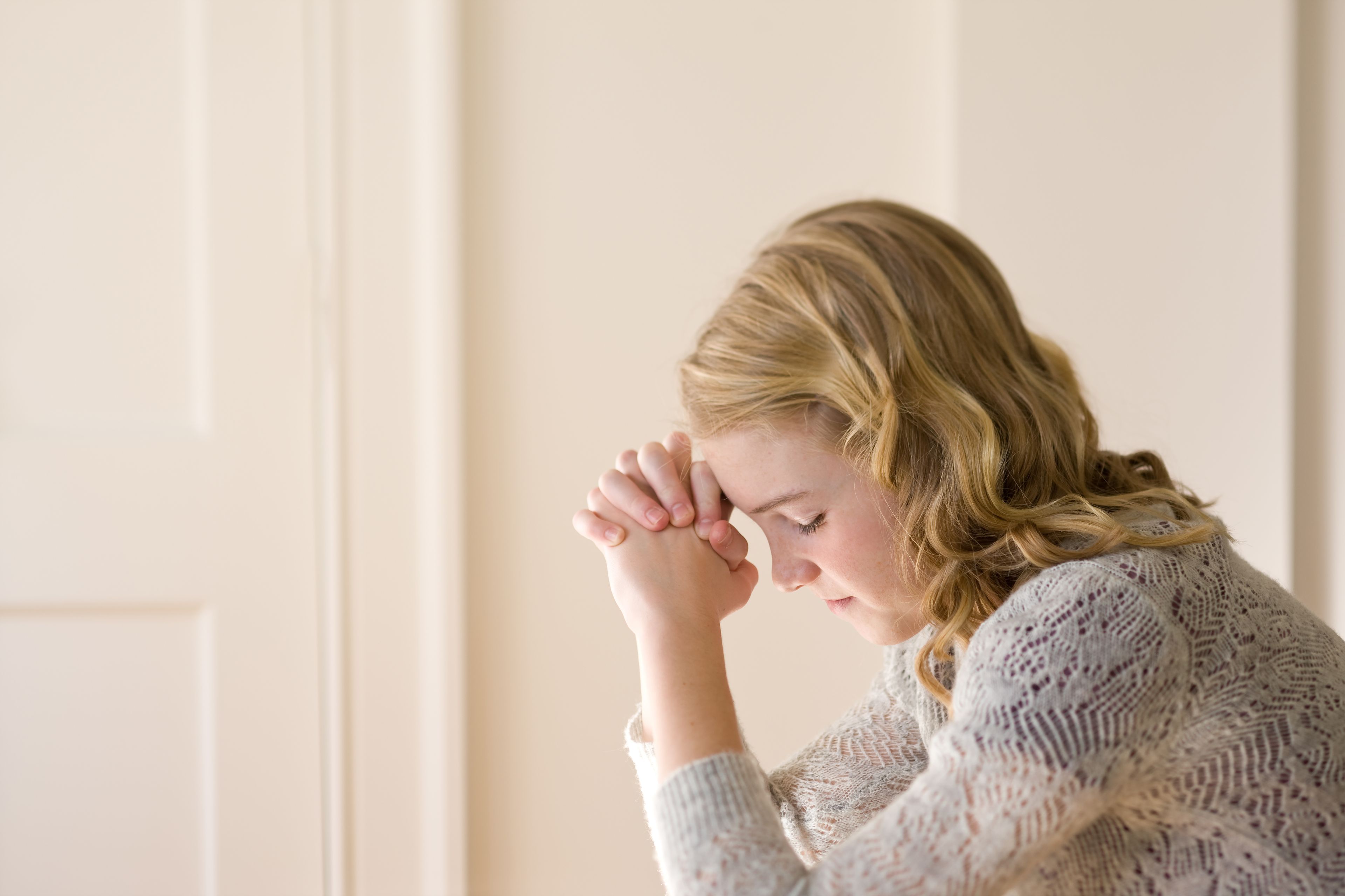 A young woman kneels in prayer.
