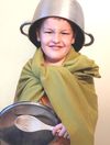 Boy with a blanket cape, a cooking-pot helmet, and a pot lid shielf