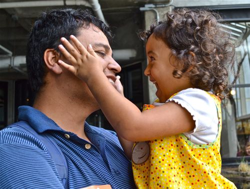 Girl playing with her father's face.