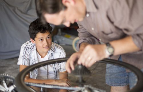 father working on bicycle with son