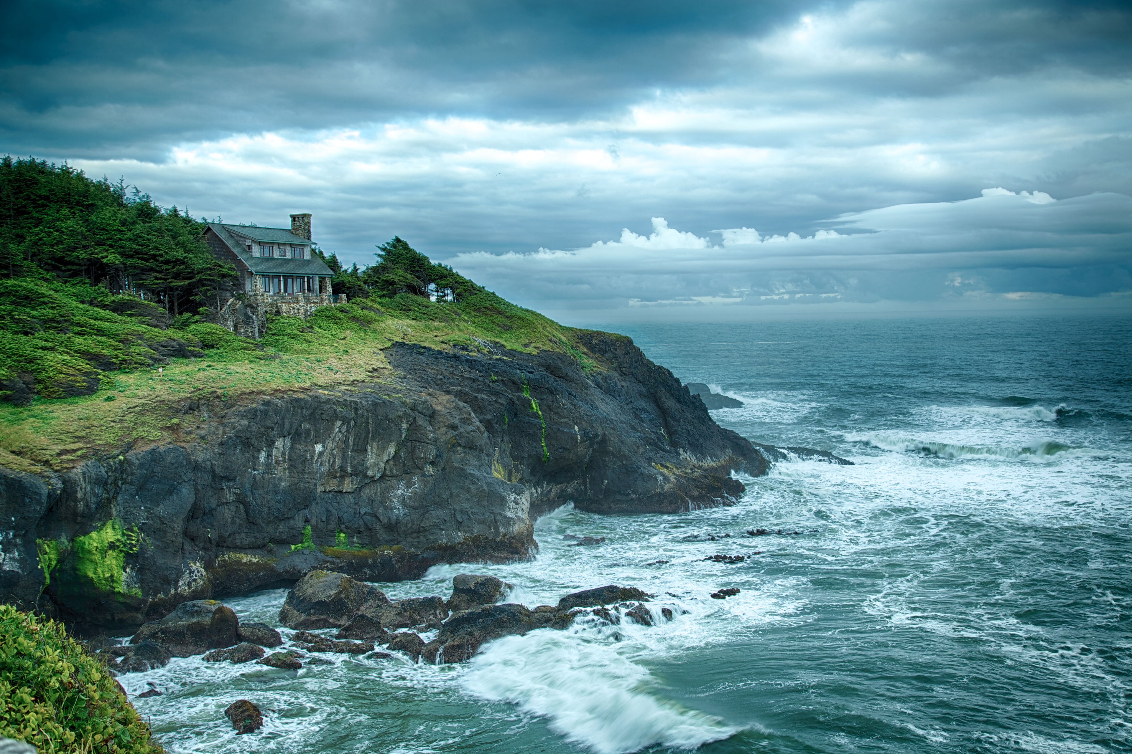 A house sits on a rocky cliff and coastline.