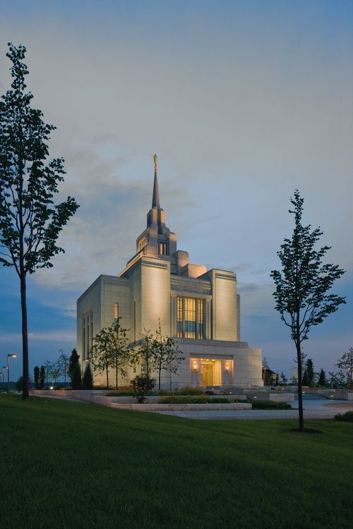 A portrait of the Kyiv Ukraine Temple illuminated at night, with several trees on the temple grounds in view.