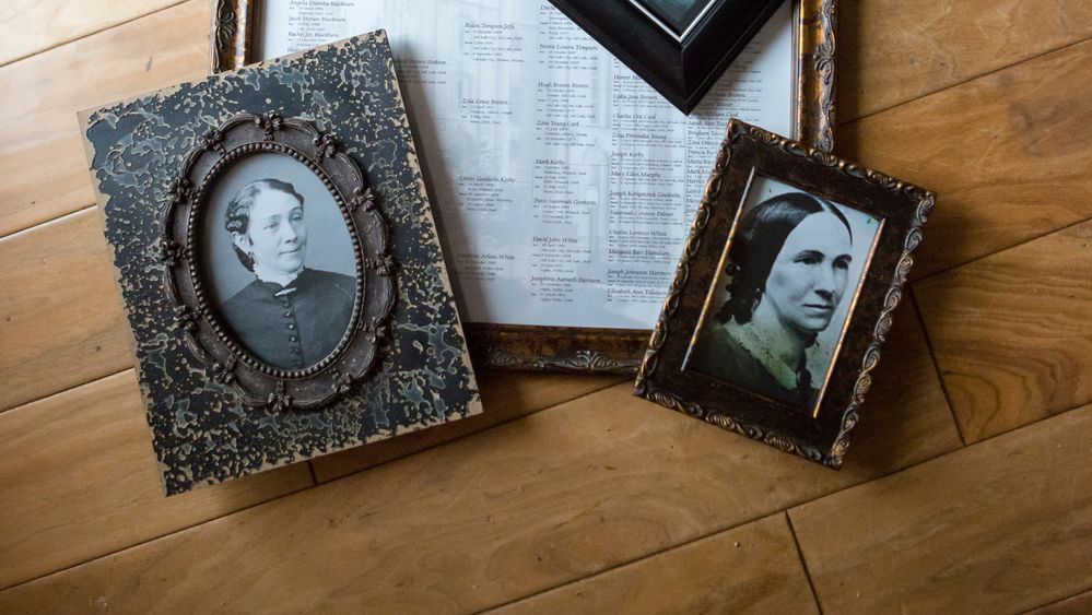 Two framed black-and-white photos of women lay on top of a family tree.  