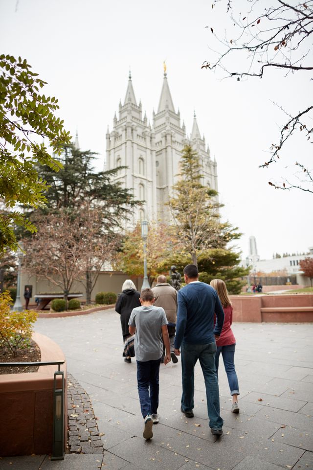 A family is together. They are walking around Temple Square talkig and laughing. You can see the Salt Lake Temple behind them.