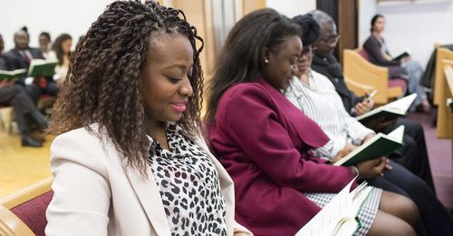 people sitting in church with hymnbooks open